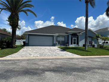 Single-story home with gray exterior, paved driveway, and lush landscaping at 148 Joewood Trl, Davenport, FL 33837