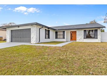 Updated single story home with gray garage door and orange front door at 202 Cobalt Dr, Kissimmee, FL 34758
