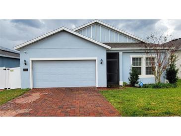Light blue house with a red brick driveway and a two-car garage at 421 Disa Dr, Davenport, FL 33837