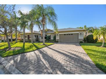 Single-story home with paver driveway, landscaping, and palm trees at 135 Lemon Grove Dr, Poinciana, FL 34759