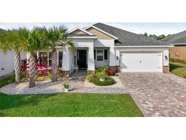 Single-story home with white exterior, landscaping, and paver driveway at 2937 Bella Flore Ter, New Smyrna Beach, FL 32168