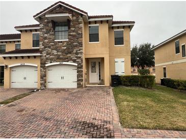 Two-story townhome with two-car garage and brick paved driveway at 1427 Pacific Rd, Kissimmee, FL 34759