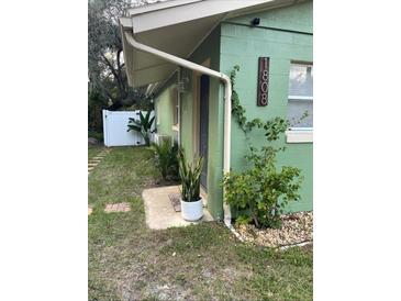 Green house exterior with walkway, landscaping, and white fence at 1808 S Mulberry Ave, Sanford, FL 32771