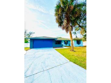 Ranch-style home with blue garage door and palm tree at 520 Carlsbad Dr, Kissimmee, FL 34758