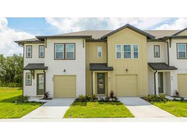 Two-story townhome with neutral siding, attached garage, and landscaping at 607 Longboat Dr, Davenport, FL 33896