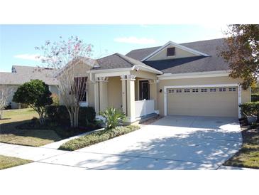 Tan house with a two-car garage and manicured landscaping at 6826 Goldflower Ave, Harmony, FL 34773