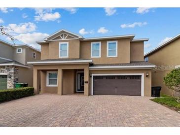 Two-story house with brown exterior, a three-car garage, and a paved driveway at 7617 Wilmington Loop, Kissimmee, FL 34747