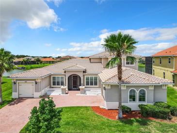 Two-story house with tile roof, large windows, and a brick driveway at 870 Spinnaker Way, Kissimmee, FL 34746