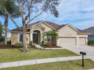 Tan house with brown roof, three-car garage, and landscaped yard at 125 Viola Dr, Auburndale, FL 33823