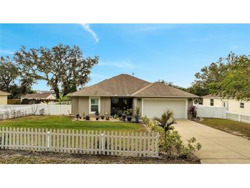 Cute one-story house with a white picket fence and a well-manicured lawn at 203 North Cir, Davenport, FL 33837