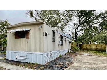 Tan mobile home with mature trees and a fenced backyard at 215 4Th St, Orlando, FL 32824