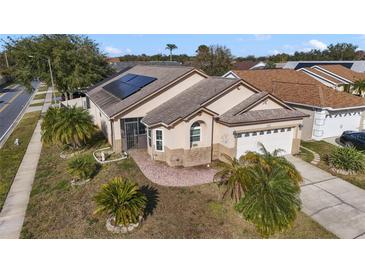 One-story home with solar panels, landscaped yard, and attached garage at 4525 Oakbrook Ct, Kissimmee, FL 34746