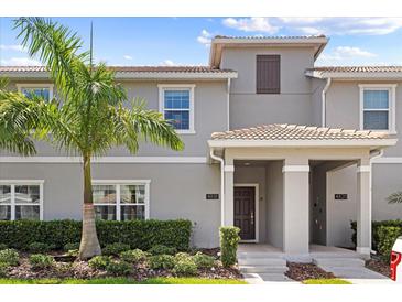 Two-story townhome with gray exterior, palm tree, and landscaping at 4818 Memories Ln, Kissimmee, FL 34746