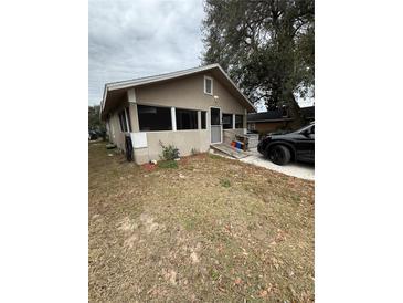 Tan house with a screened porch, small yard, and a car parked in the driveway at 704 N 8Th St, Haines City, FL 33844