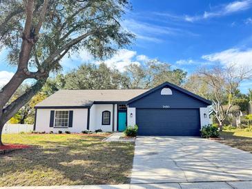 Newly renovated single-story home featuring a teal front door and a navy blue garage door at 7450 Crooked Lake Cir, Orlando, FL 32818