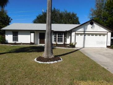 White single-story house with a two-car garage and well-maintained lawn at 1972 S Old Mill Dr, Deltona, FL 32725