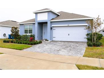 One-story home with gray exterior, white garage door, and landscaped yard at 1280 Tupelo Trl, Haines City, FL 33844