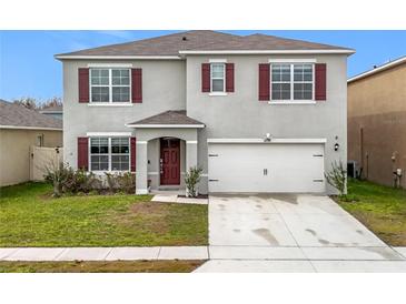 Charming two-story home featuring a well-maintained lawn, attached two-car garage and red window shutters at 1634 Reddish Egret Ct, Davenport, FL 33897