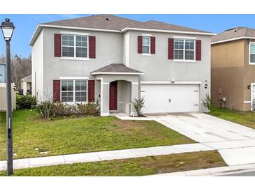 Charming two-story home with red shutters, a well-maintained lawn, and an attached two-car garage at 1634 Reddish Egret Ct, Davenport, FL 33897