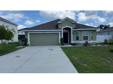 Green house with two-car garage and landscaped lawn at 1015 Sabine Pl, Kissimmee, FL 34759
