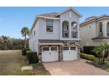 Beautiful two-story home with a stone-accented facade, a balcony, and a two-car garage at 733 Desert Mountain Ct, Reunion, FL 34747
