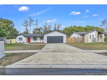 Newly renovated home with a red door and a spacious driveway at 8607 Tarragon Dr, Orlando, FL 32825
