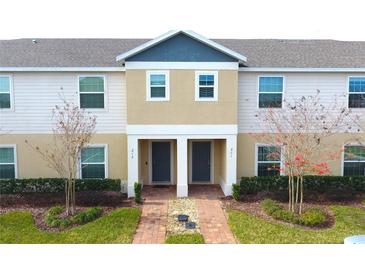 Tan two-story townhome with gray doors and landscaping at 215 Annabelle Way, Davenport, FL 33837