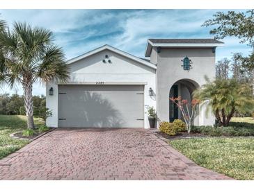 One-story home with gray garage door, landscaping, and brick driveway at 2285 Palm Tree Dr, Kissimmee, FL 34759