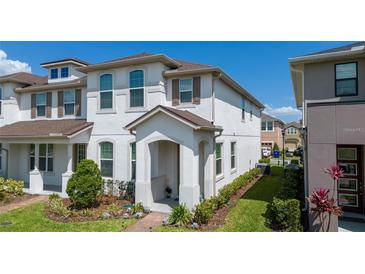 Charming townhouse featuring a covered entryway, well-maintained lawn, and elegant architectural details at 2449 Varenna Loop, Kissimmee, FL 34741