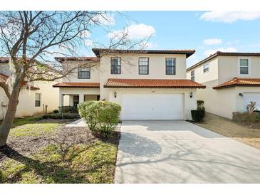 Inviting two-story home featuring a two-car garage, landscaped front yard, and a classic tile roof at 2818 Roccella Ct, Kissimmee, FL 34747