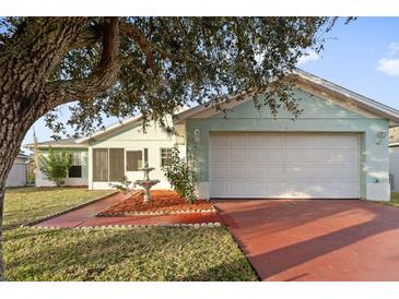 House exterior featuring a light teal color, attached garage, and well-manicured lawn at 511 Cardinal Dr, Kissimmee, FL 34759