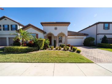 Beautiful two-story home with a well-manicured lawn and brick driveway at 9067 Arbors Edge Trl, Windermere, FL 34786