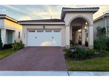 Tan house with white garage door, red brick driveway and landscaping at 9720 Bucklow Hill Dr, Orlando, FL 32832