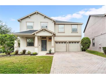 Charming two-story home featuring a brick driveway, manicured lawn and a welcoming covered porch at 9786 Lake District Ln, Orlando, FL 32832