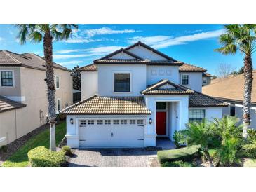 Two-story home with tile roof, white exterior, and a two-car garage at 1320 Moss Creek Ln, Davenport, FL 33836