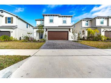 Two-story house with brown garage door and paver driveway at 1765 Petiole Pl, Kissimmee, FL 34744