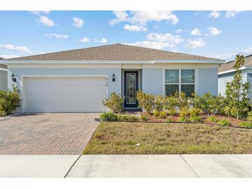 One-story home with light-blue exterior, brick driveway, and landscaped lawn at 2124 Live Oak Lake Rd, St Cloud, FL 34771