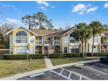 Two-story condo building with yellow exterior and palm trees at 2452 Sweetwater Club Cir # 27, Kissimmee, FL 34746