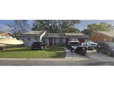 Single story home with solar panels, well-manicured lawn, and multiple vehicles in driveway at 372 La Paz Dr, Kissimmee, FL 34743