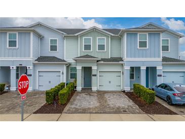 Three-story townhome with two-car garage and landscaped front yard at 4806 Tribute Trl, Kissimmee, FL 34746