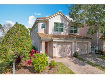 Two-story townhome with two-car garage, landscaped yard, and brick driveway at 8318 Quimby Cir, Davenport, FL 33896