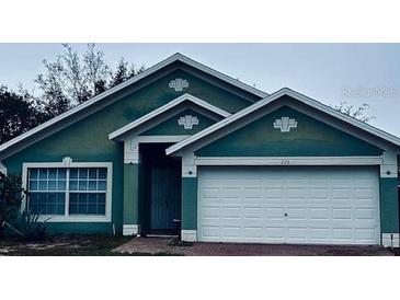 Teal house with white garage door and landscaping at 228 Remington Pl, Haines City, FL 33844