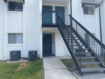 Condo exterior features stairs and a white facade, offering a welcoming entrance at 4149 S Semoran Blvd # 10, Orlando, FL 32822