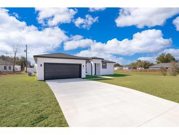 Single-story home with a two-car garage and landscaped lawn at 4690 Sw 139Th Place, Ocala, FL 34473
