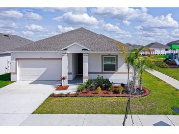 White house with gray roof, landscaping, and driveway at 566 Pawnee Ct, Haines City, FL 33844
