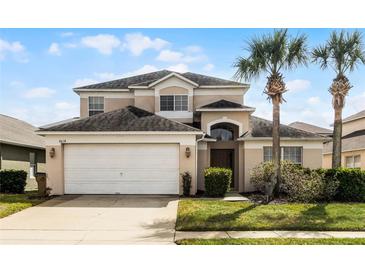 Two-story house with a two-car garage and palm trees in the front yard at 8614 La Isla Dr, Kissimmee, FL 34747