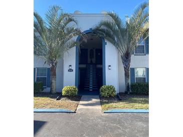 Two-story condo building with palm trees and a central staircase at 1014 Plantation Dr # A9, Kissimmee, FL 34741