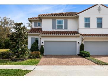 Two-story townhome with gray garage doors and brick driveway at 2935 Rapollo Ln, Apopka, FL 32712