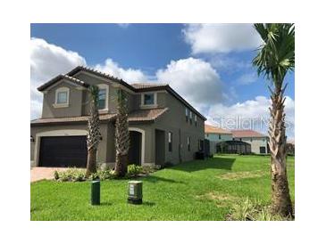 Two-story house with a gray exterior, two-car garage, and a neatly landscaped lawn at 5465 Misty Oak Cir, Davenport, FL 33837