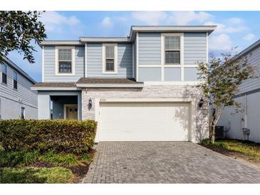 Two-story house with light blue siding, white garage door, and landscaped front yard at 8939 Zurich Ln, Kissimmee, FL 34747
